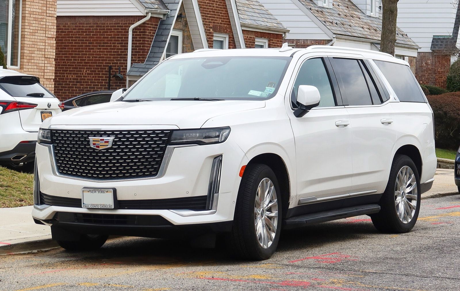 White Cadillac Escalade SUV parked on a residential street, front three-quarter view
