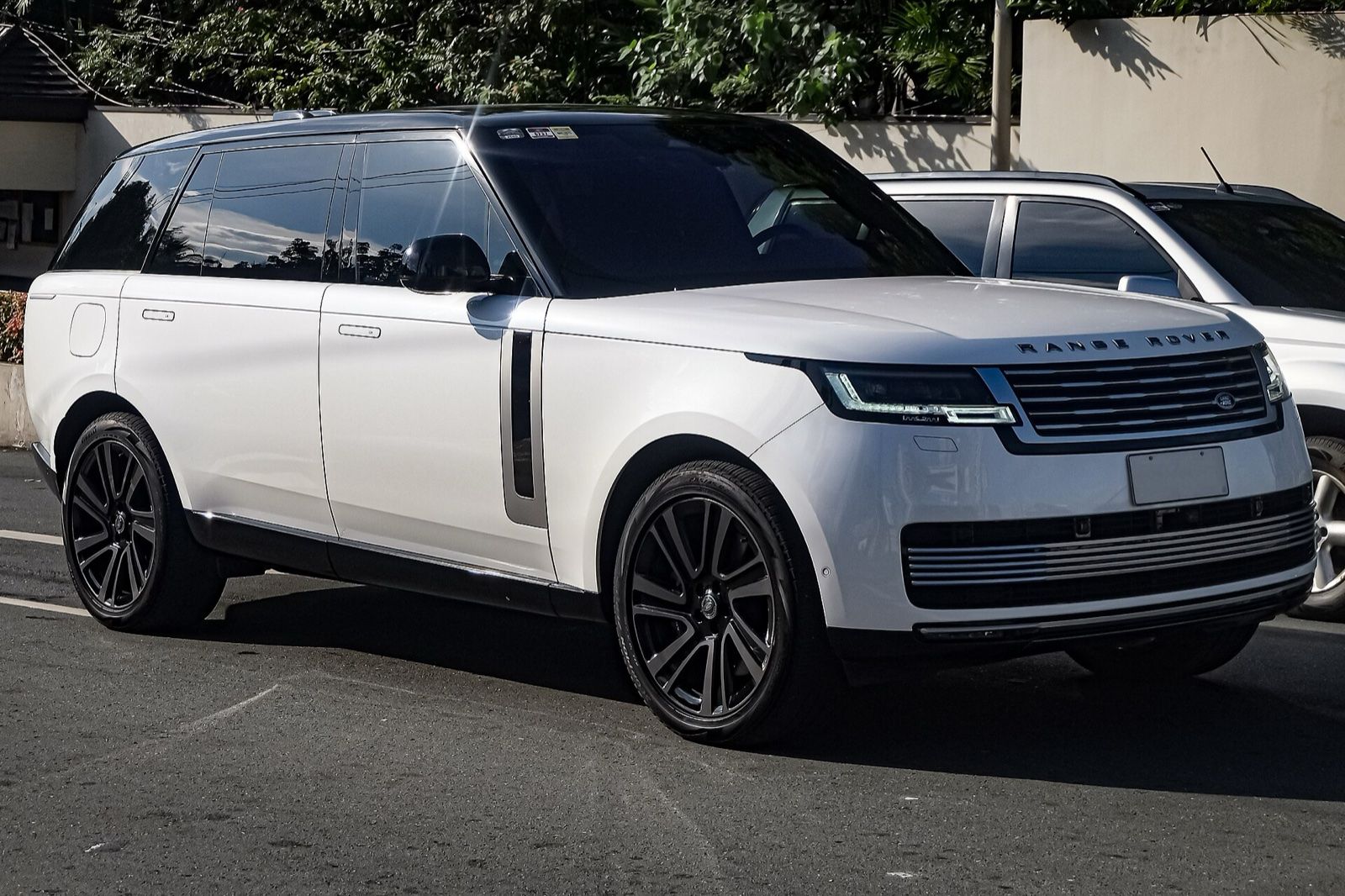 White Range Rover (L460) SUV parked on a street, front three-quarter view