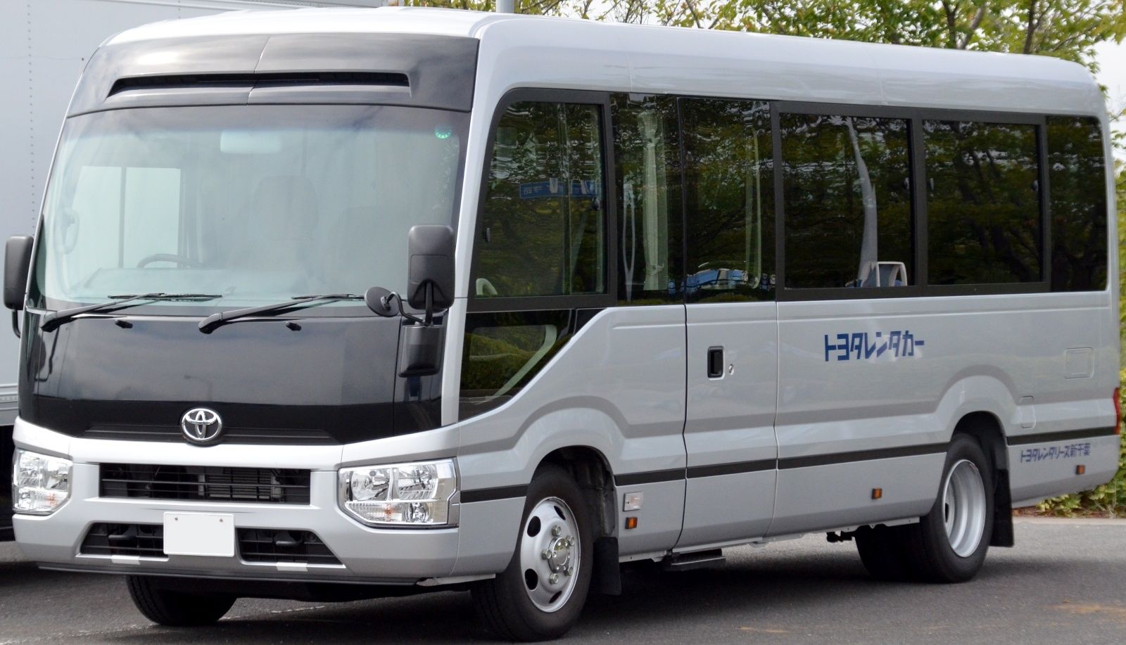 Silver and white Toyota Coaster minibus, front three-quarter view