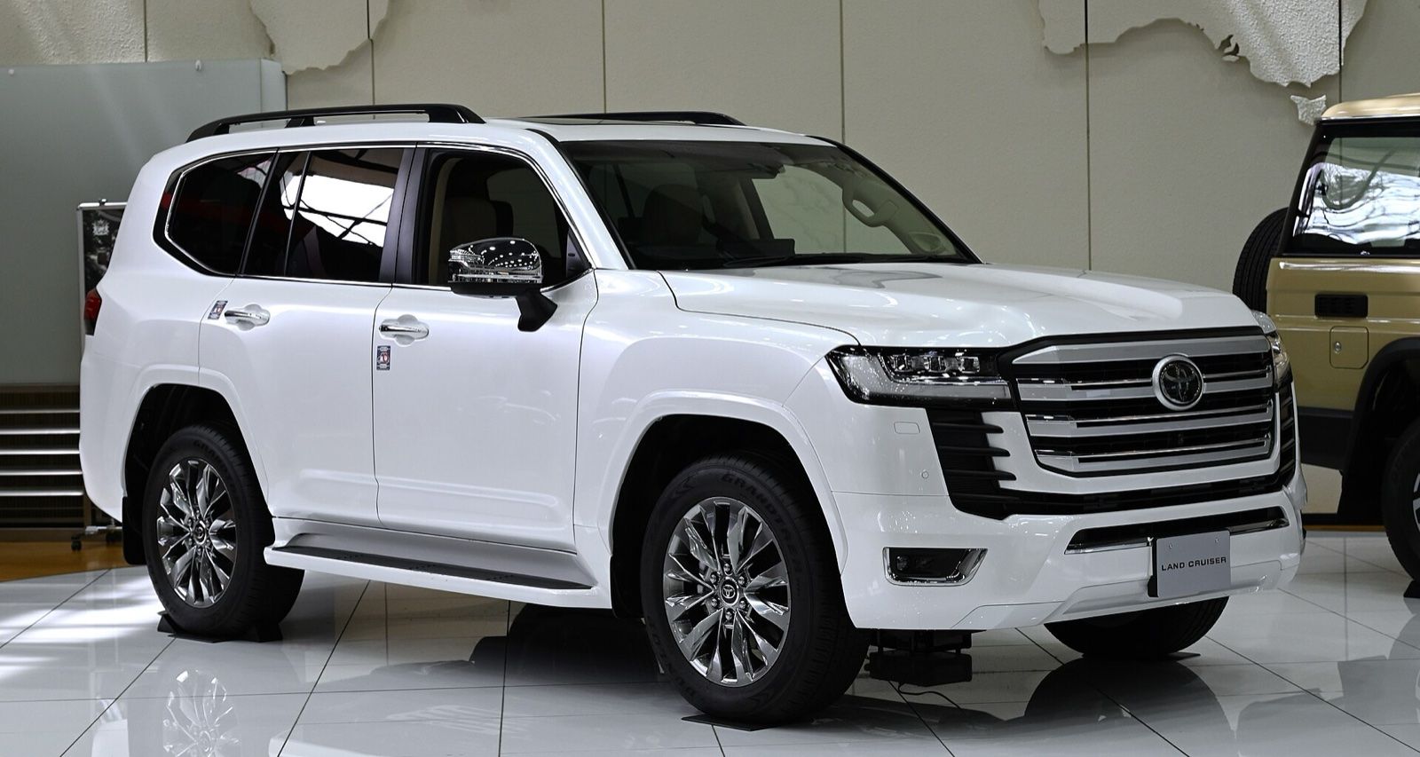 White Toyota Land Cruiser 300 SUV in a showroom, front three-quarter view