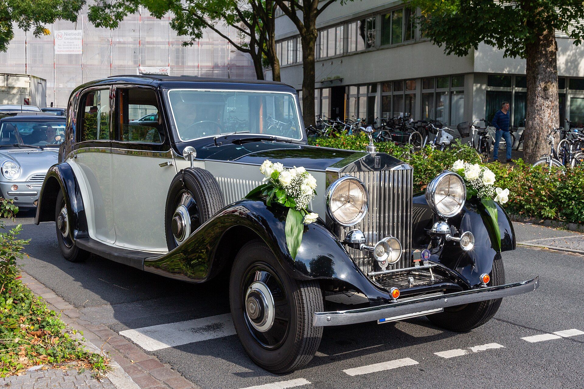 Classic Rolls Royce wedding car decorated with white flower arrangements on the bonnet